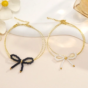 Pulsera de doble cadena dorada con lazos de cuentas negros y blancos y cierre ajustable