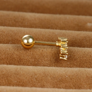 Close-up of golden curved cartilage stud with sparkling zircon and screw ball back