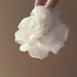 Vista macro dettagliata di un grande accessorio a fiore in tessuto bianco 3D in organza