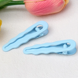 Close-up of blue wavy water-drop hair clips on a soft textured background with tulips