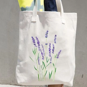 White canvas shoulder bag with purple lavender floral print carried by a model