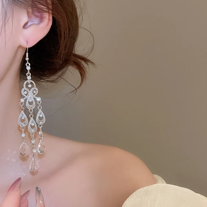 Close-up of elegant silver tassel earrings with crystal teardrops worn by a model