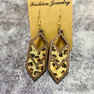 Detail of geometric wooden drop earrings featuring leopard print inlay on kraft card