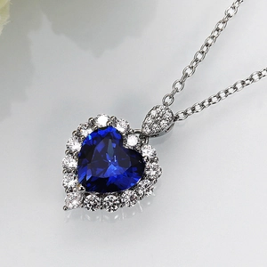 Close-up of royal blue heart gemstone necklace with white zircon halo and silver chain