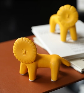 Detail of creative ceramic lion sculptures with a modern matte yellow finish for home decor