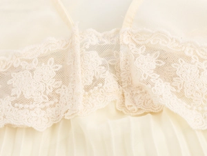 Dettaglio del pizzo floreale e texture in chiffon a pieghe su abito lungo giallo