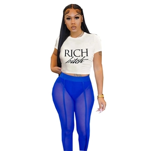 Dettaglio di crop t-shirt bianca con stampa RICH e leggings in mesh blu sul modello