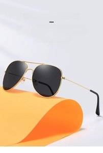 Fashion aviator sunglasses with gold metal frames and dark lenses on creative orange backdrop