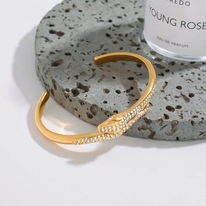 Macro view of gold snake-shaped open bracelet with shimmering zircon pave stones