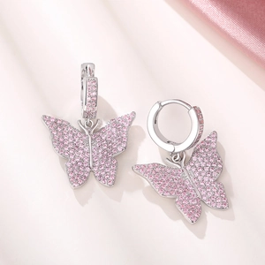 Detailed view of micro-pave pink zircon butterfly earrings on soft pink silk