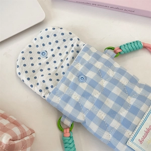 Close-up of blue gingham quilted bag showing inner lining, snap button and woven strap