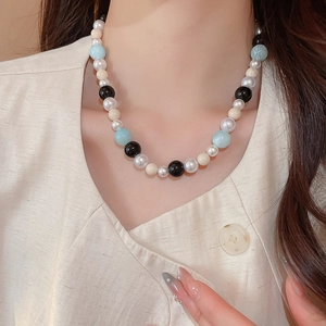 Detailed close-up of a pearl and mixed colored glass bead necklace on a neck model