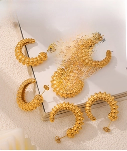 Detailed view of C-shaped gold-plated earrings with unique 3D grain texture and metallic finish