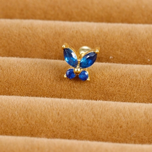 Macro shot of gold butterfly stud earring with blue zircons on velvet display tray