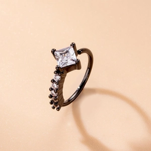 Detail shot of black square-cut zircon ring with micro-paved accents on beige background