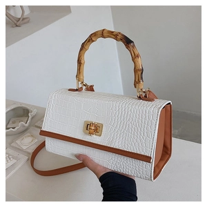 Detail of crocodile pattern white PU handbag with bamboo handle and gold lock closure