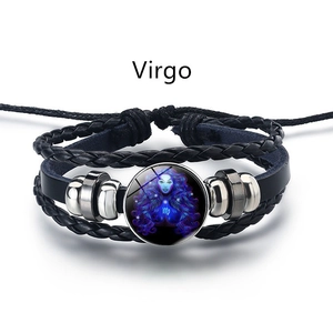 Détail du bracelet en cuir tressé avec le signe de la Vierge et un cabochon en verre bleu