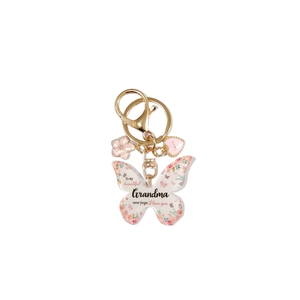 Détail du porte-clés papillon avec motif floral et texte gravé pour grand-mère