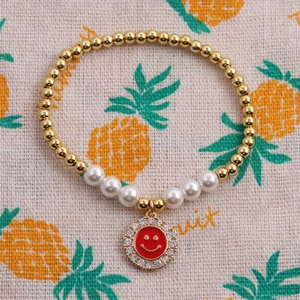 Detail view of a pearl bead bracelet featuring a red zircon smiley face charm