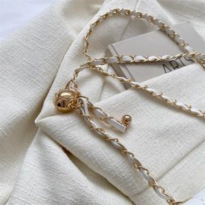 Quilted white leather chain strap with golden ball adjustment buckle on tweed background
