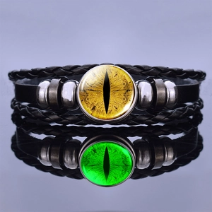 Close-up of steampunk leather bracelets featuring luminous yellow and green dragon eye glass