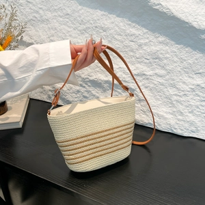 Straw woven bucket bag with brown stripes and leather shoulder strap for beach holidays