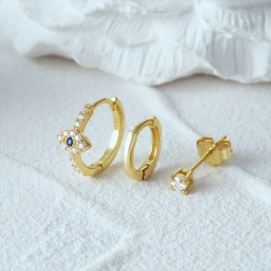 Detailed macro view of S925 sterling silver gold evil eye earrings set with blue gems