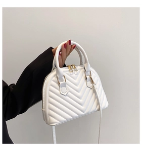 Detail of white chevron quilted shell bag with golden zipper and leather top handle