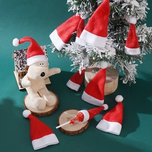 Mini red and white Christmas hats for dolls and candy decorations on snowy tree