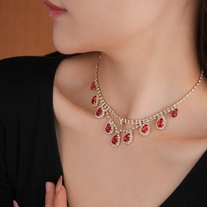 Close-up of a gold necklace with red teardrop rhinestones and layered diamond fringes
