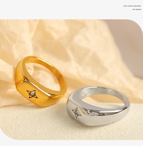 Detail of square gold and silver rings with North Star zircon stone on soft white fabric