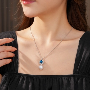 Dettaglio della collana vintage con gemma blu e ciondolo di perla bianca su catena argento