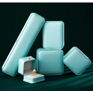 Stack of elegant light blue jewelry boxes for rings and necklaces on dark velvet