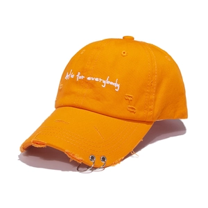 Distressed orange baseball cap with white embroidery and metal rings on brim
