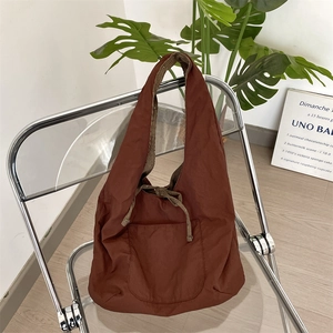 Detail of corduroy shoulder bag showing side pocket and striped inner lining on a chair