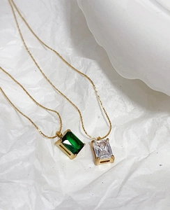 Detail of square emerald green and white zircon pendants on 18k gold plated chains