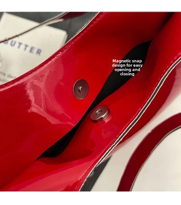 Macro shot of magnetic snap closure on a red patent leather heart-shaped handbag
