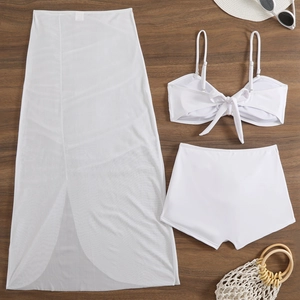 Detailed flat lay of white three-piece swimsuit with mesh skirt and vacation accessories