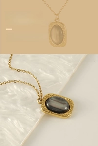 Detail of square gold pendant necklace with oval tiger eye stone on marble surface