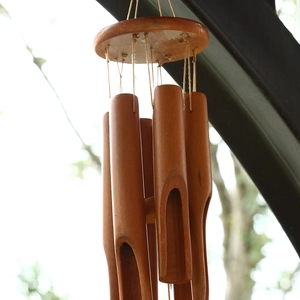 Outdoor low-angle view of a natural bamboo wind chime with six tubes and round wooden top