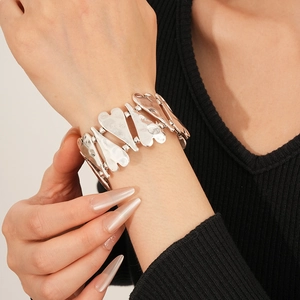 Vue détaillée du bracelet large cœurs argentés à texture martelée sur fond noir tricoté