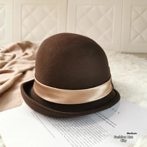 Close-up of wool felt bowler hat with a champagne satin ribbon on a magazine