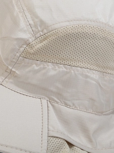 Close-up of beige ripstop nylon fabric with breathable mesh and durable double stitching