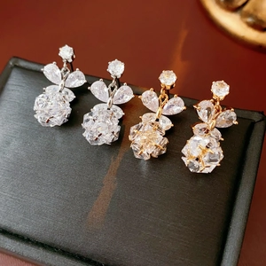 Détail de boucles d'oreilles pendantes en argent et or avec pierres en zircone cubique