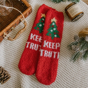 Detail of red coral fleece Christmas socks with tree pattern and Keep Truth text