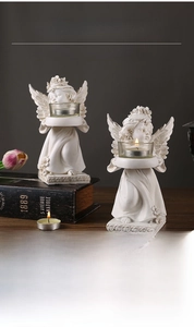 Close-up of vintage resin angel candle holders with glass cups on wooden table