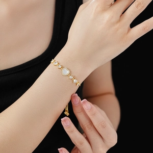 Detail of gold heart bracelet with white mother-of-pearl and adjustable drawstring closure