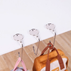Portable silver metal desk hooks for school bags shown on a white tabletop edge