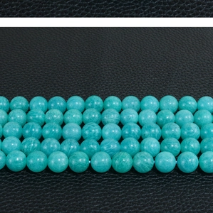 Macro shot of natural turquoise round loose beads on a black leather textured background