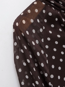 Close-up of lightweight dark brown fabric with white polka dots and delicate chiffon texture